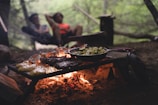 selective focus photo of skillet and meat on top of grill with fire