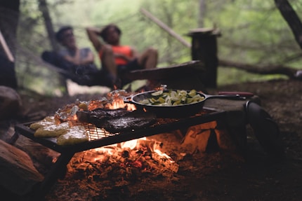 selective focus photo of skillet and meat on top of grill with fire