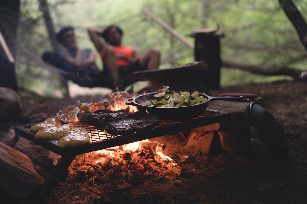 foto de foco seletivo de frigideira e carne em cima de grelha com fogo