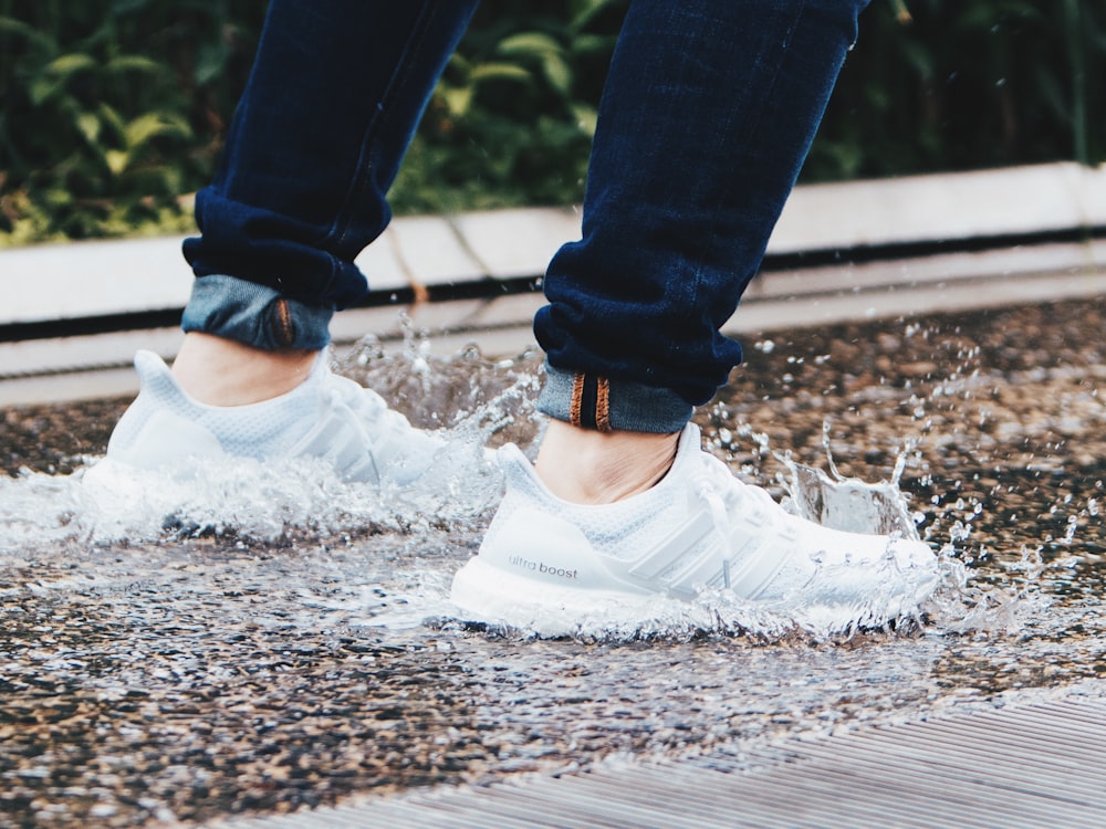 person wearing pair of gray adidas UltraBOOST low-top sneakers stepped on pool of water