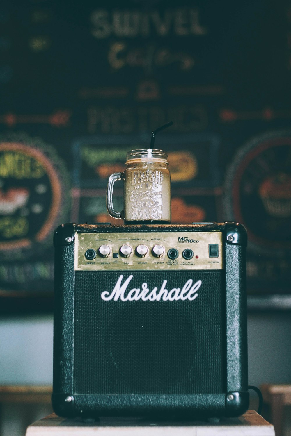 black Marshall guitar amplifier with glass mug on top filled with beverage