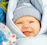 A smiling baby wrapped in a soft pastel blue blanket from Cubcare.