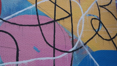 Abstract graffiti mural with bold lines and bright palette on a brick wall