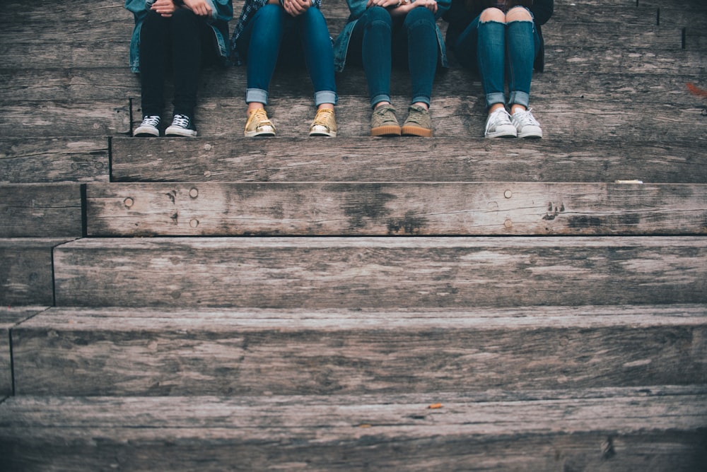 quatre personnes assises sur un escalier en bois