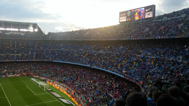 Wide shot of a packed football stadium at dusk, capturing the energy of the crowd.