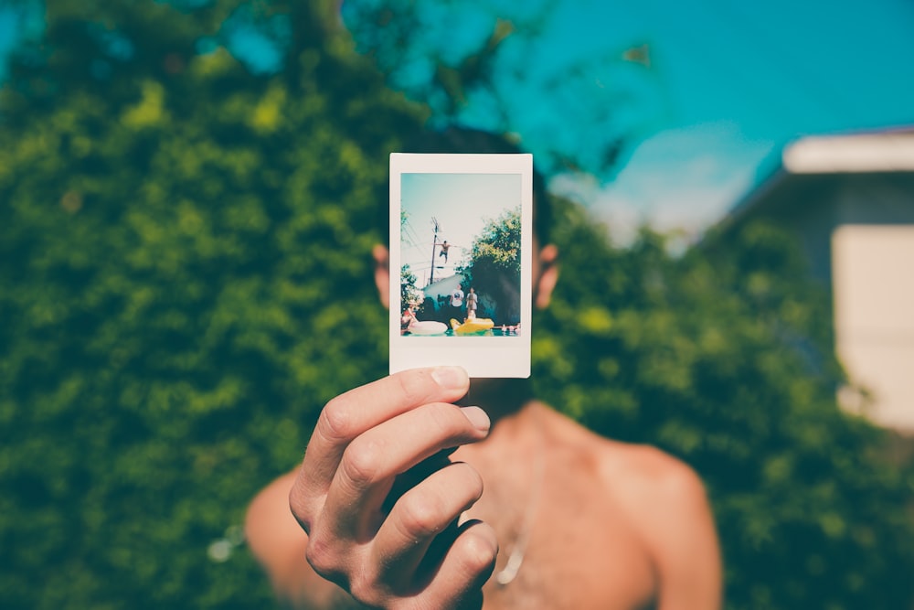 Oben-ohne-Mann hält Foto einer Person, die auf Pool taucht selektive Fokusfotografie