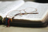 Close-up of a sleek pair of reading glasses resting on an open book.