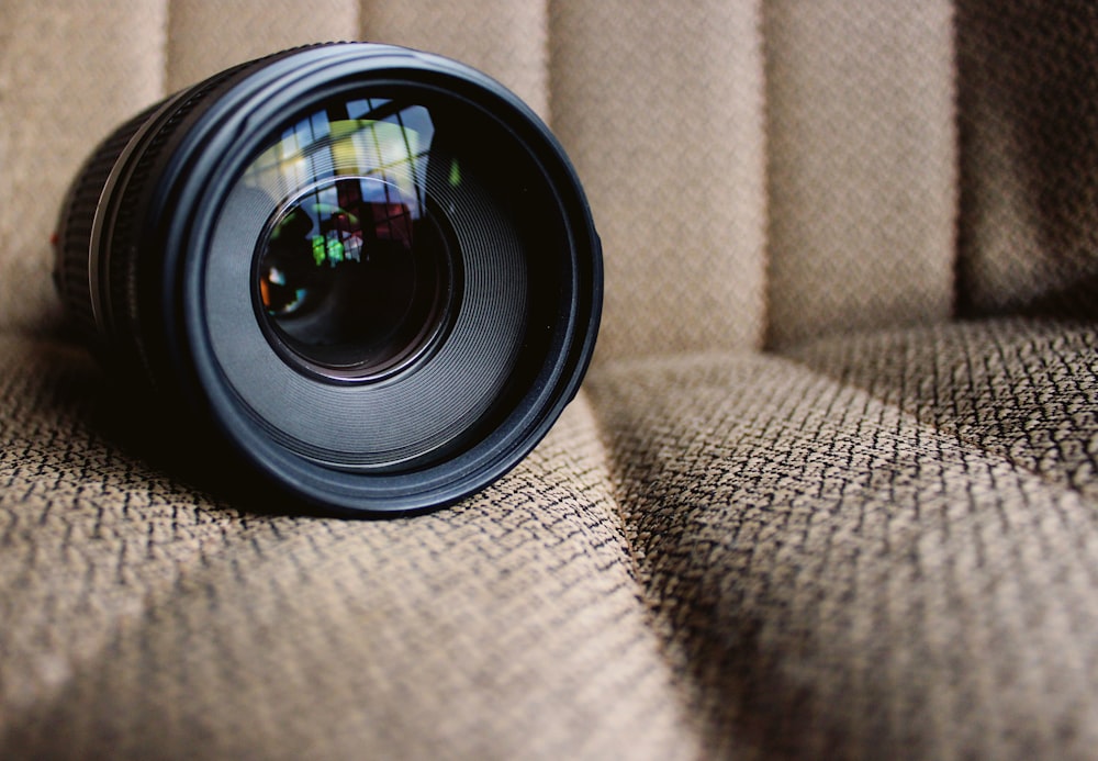 round black camera lens on brown fabric cushion