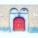 A large, wooden arched door with intricate metal hinges and a central handle is set within a stone archway. The surrounding brick wall is accentuated by two lantern-style lights and features two arched windows above the door. Electrical conduits run across the brick façade.