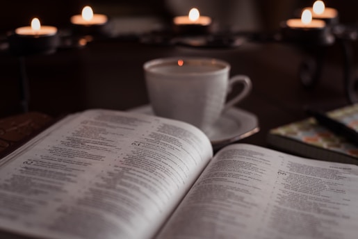 A cozy journal open on a wooden table beside a cup of tea and a soft candlelight glow.