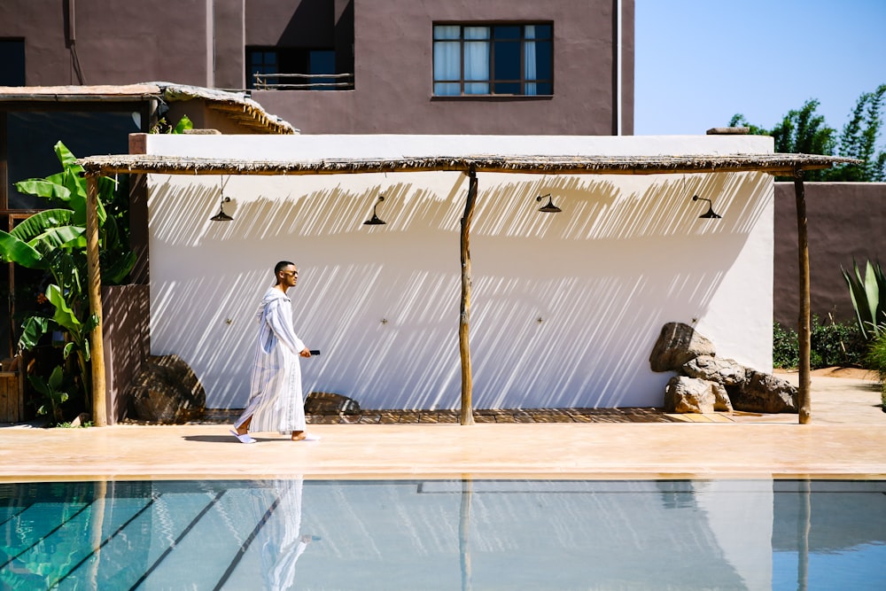 a man walking in front of a building next to a pool