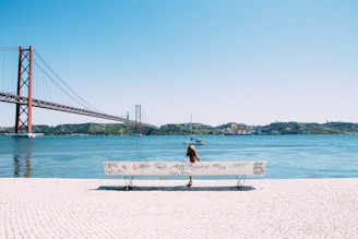 woman sitting on white bench in front of sea