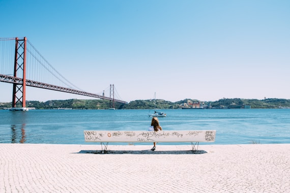 woman sitting on white bench in front of sea