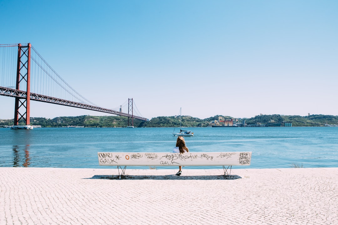 woman sitting on white bench in front of sea, Graffiti