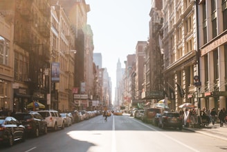 person walking on road beside cars