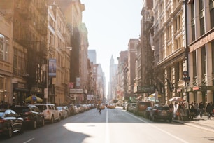 person walking on road beside cars
