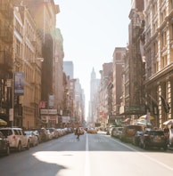 person walking on road beside cars