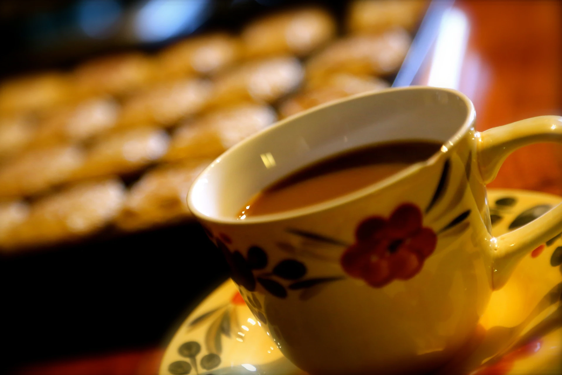 A close-up of a steaming cup of coffee next to a freshly baked breakfast pastry, set on a clean, modern table.