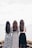 three woman looking back and facing body of water