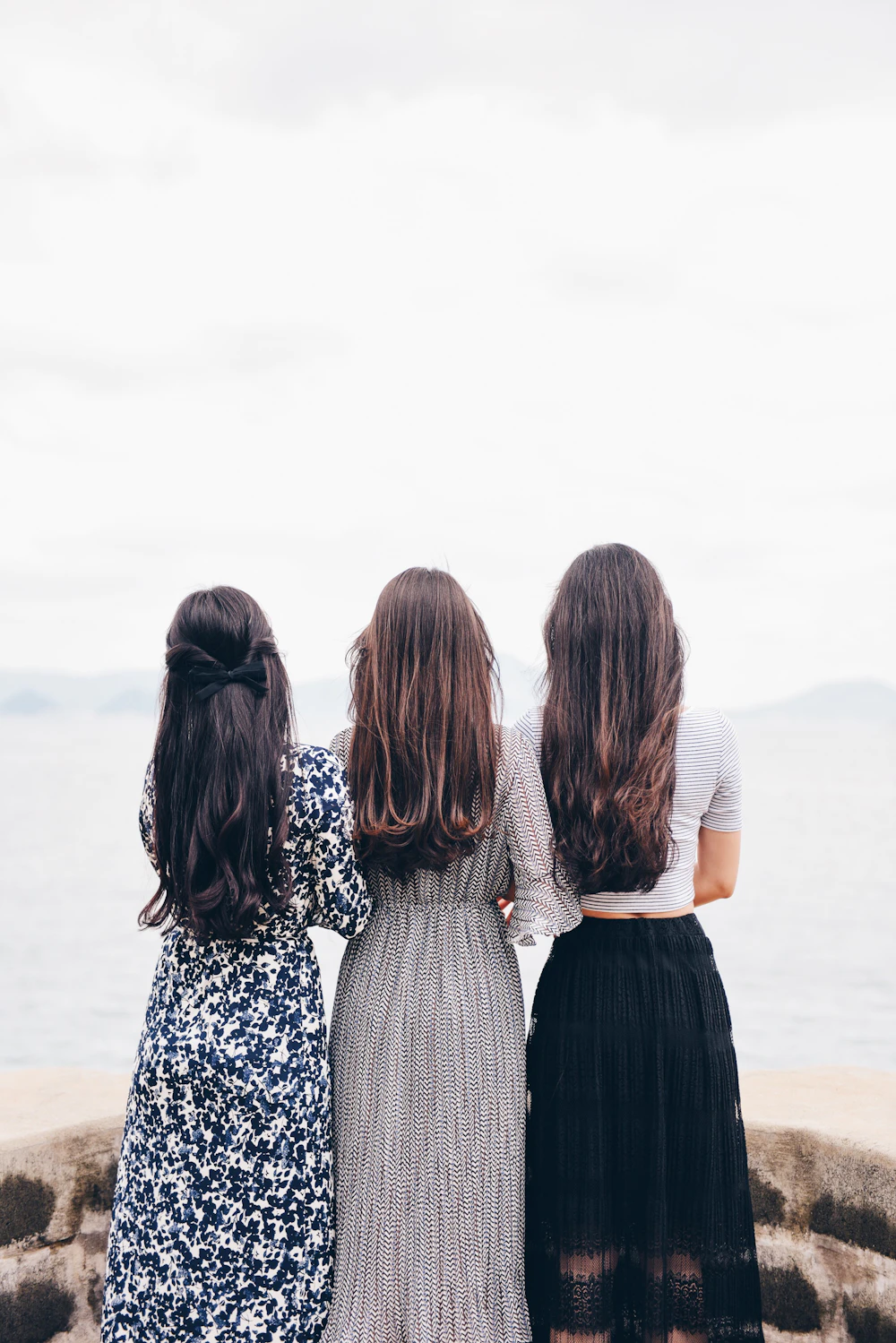 Trois femmes de dos, face à un plan d'eau entouré de nature