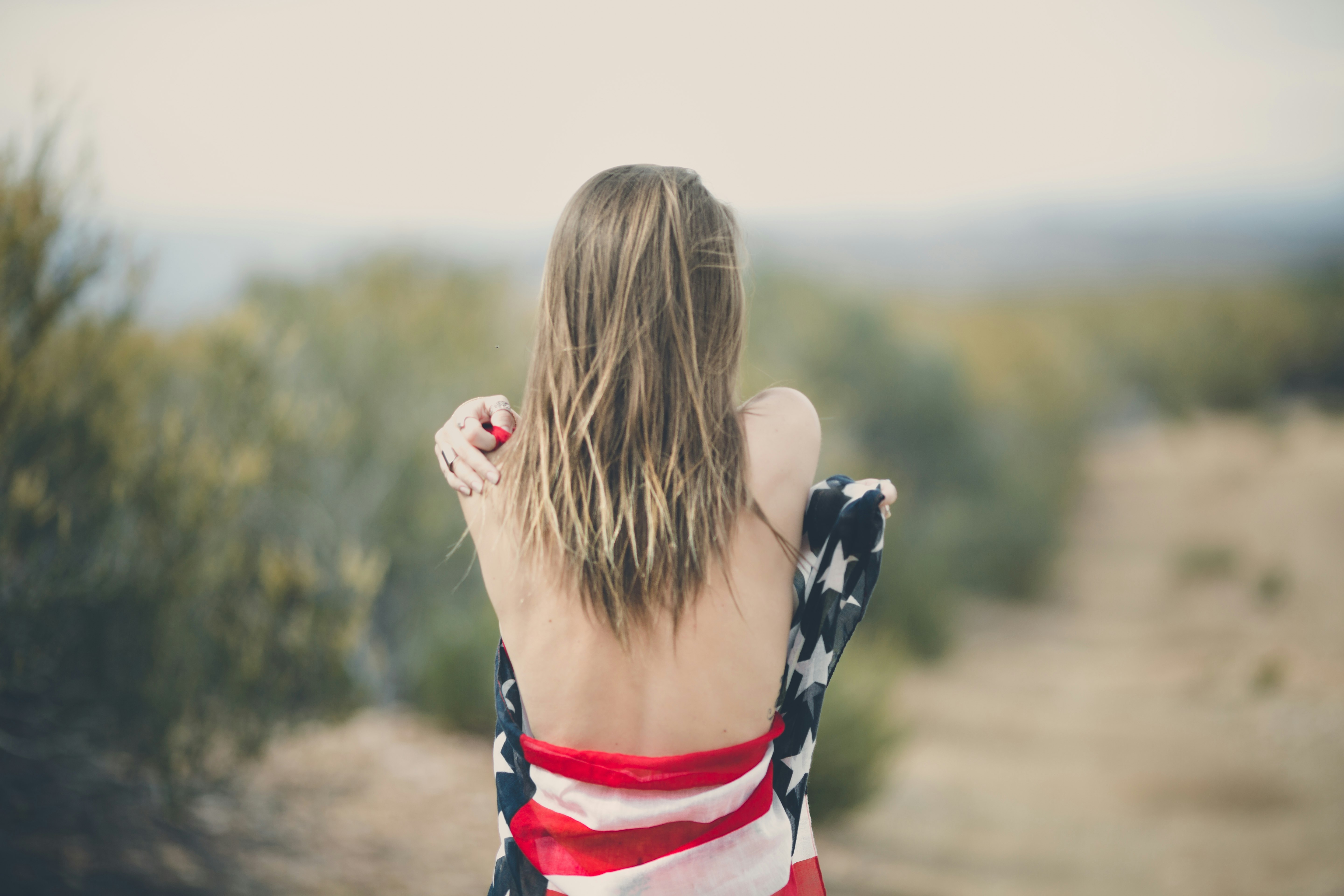 focus photography of half naked woman covering body with USA flag