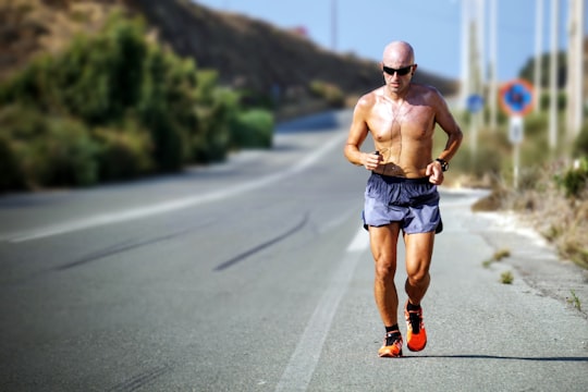 man jogging while listening using black earphones during day time in Crete Greece