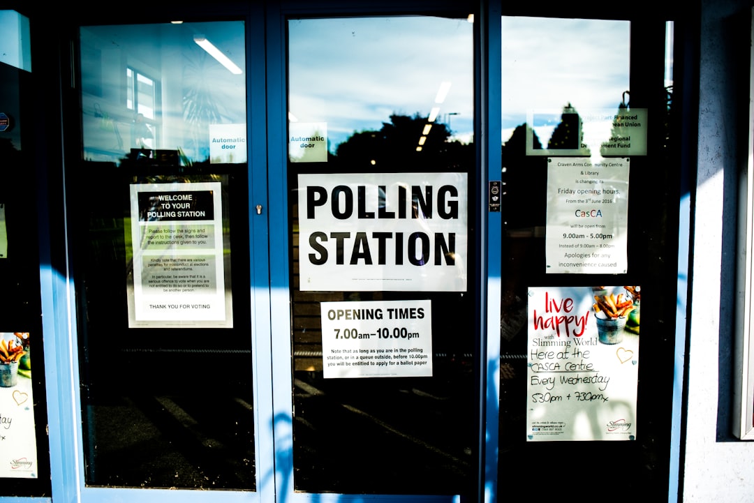 Three reflective glass doors with signs and posters reading Polling Station and Opening Times