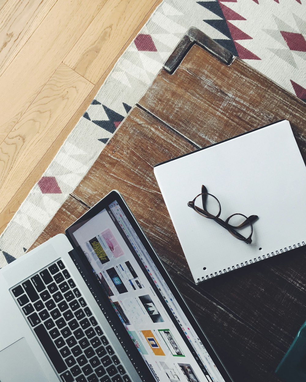 An overhead shot of a pair of glasses on a notebook next to a laptop