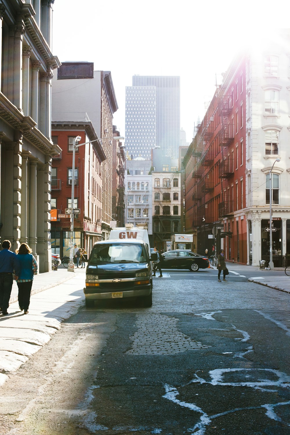 a van driving down a street next to tall buildings