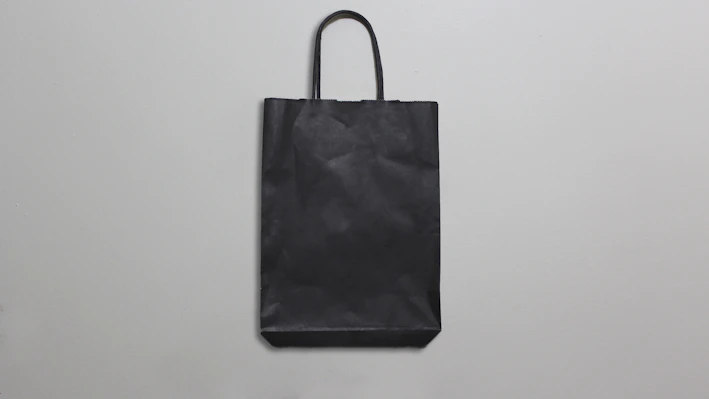 A sleek, modern shopping bag icon with subtle shadows on a white background