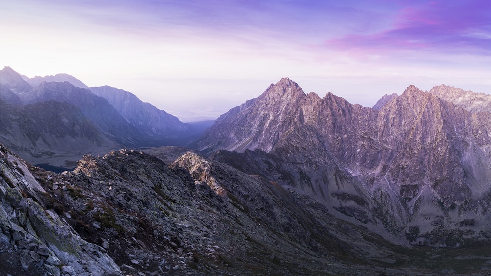 Landschaftsfotografie von Gebirgszügen unter violettem und rosafarbenem Himmel