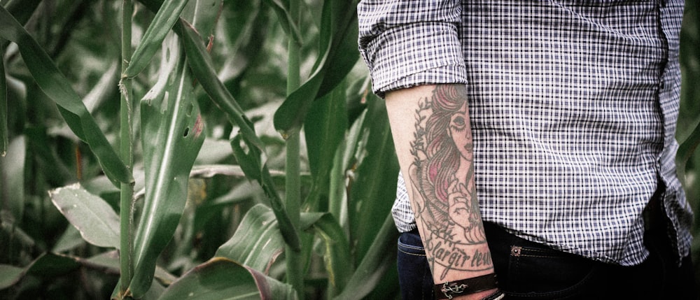 person with arm tattoo walking near green grass