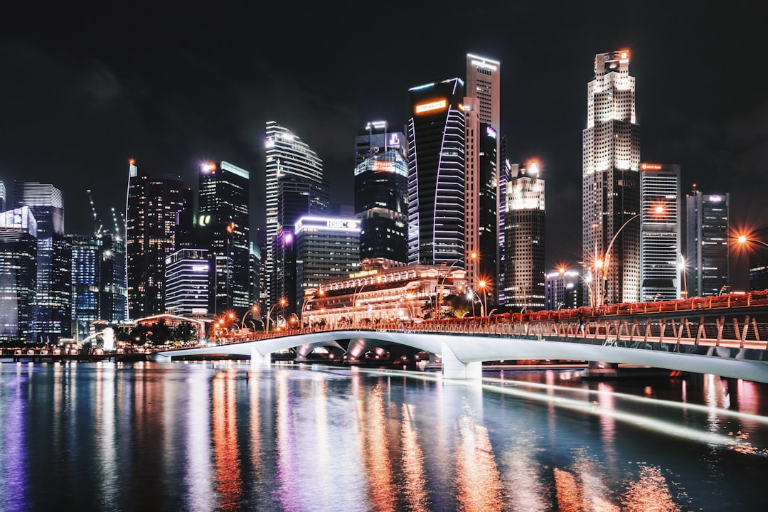 Illuminated skyscrapers near a white steel bridge at Singapore's waterfront