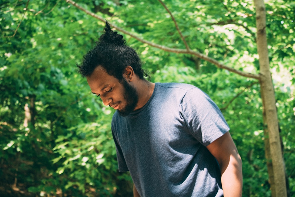 man wearing grey crew-neck t-shirt standing under tree during daytime