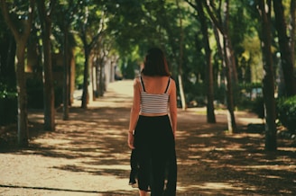 woman walking in between trees
