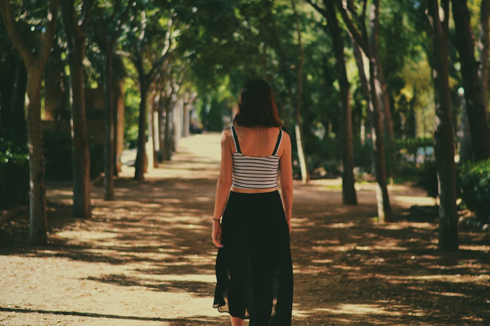 woman walking in between trees