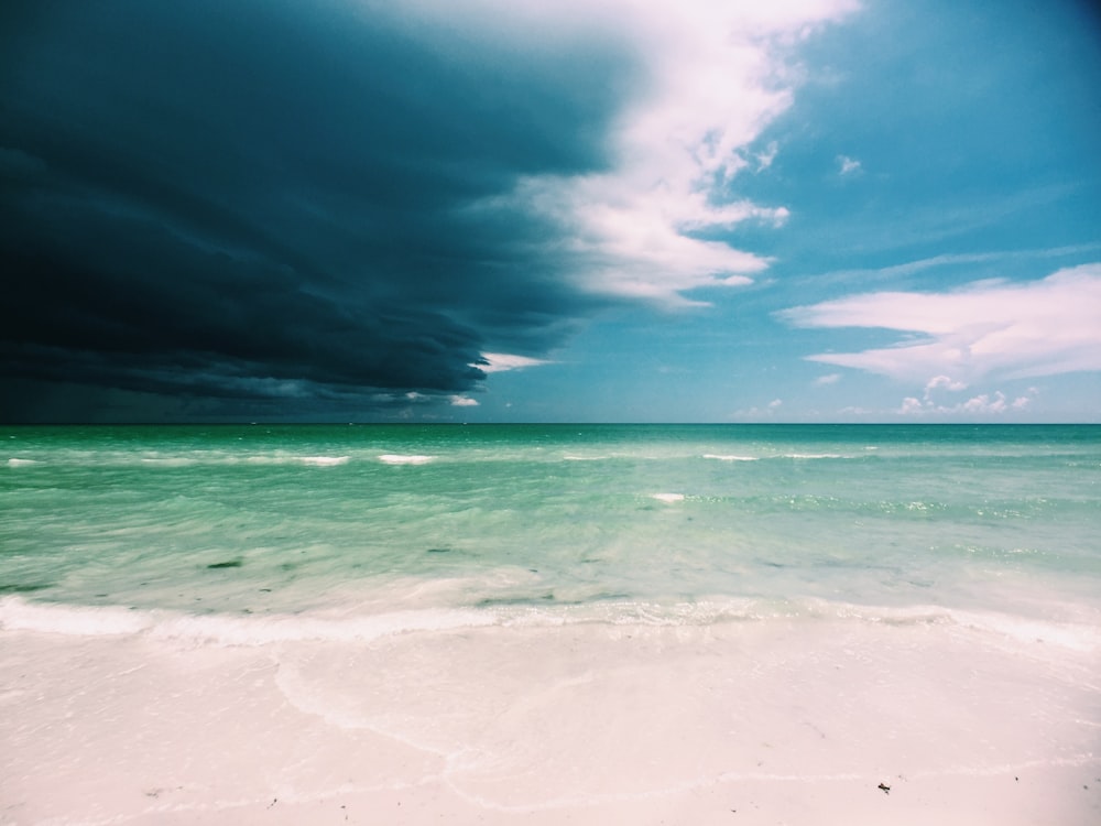 clear white sand beach under cloudy sky