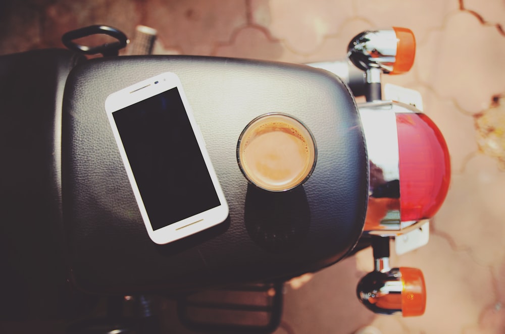 Smartphone blanco sobre asiento de moto de cuero negro