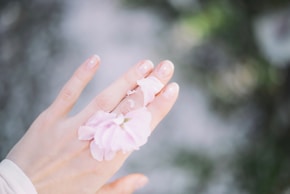 person with pink bow on hand selective focus photography