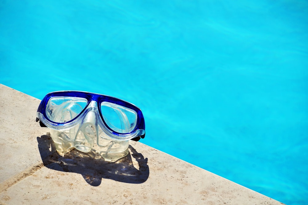 blue framed swimming goggles near pool at daytime