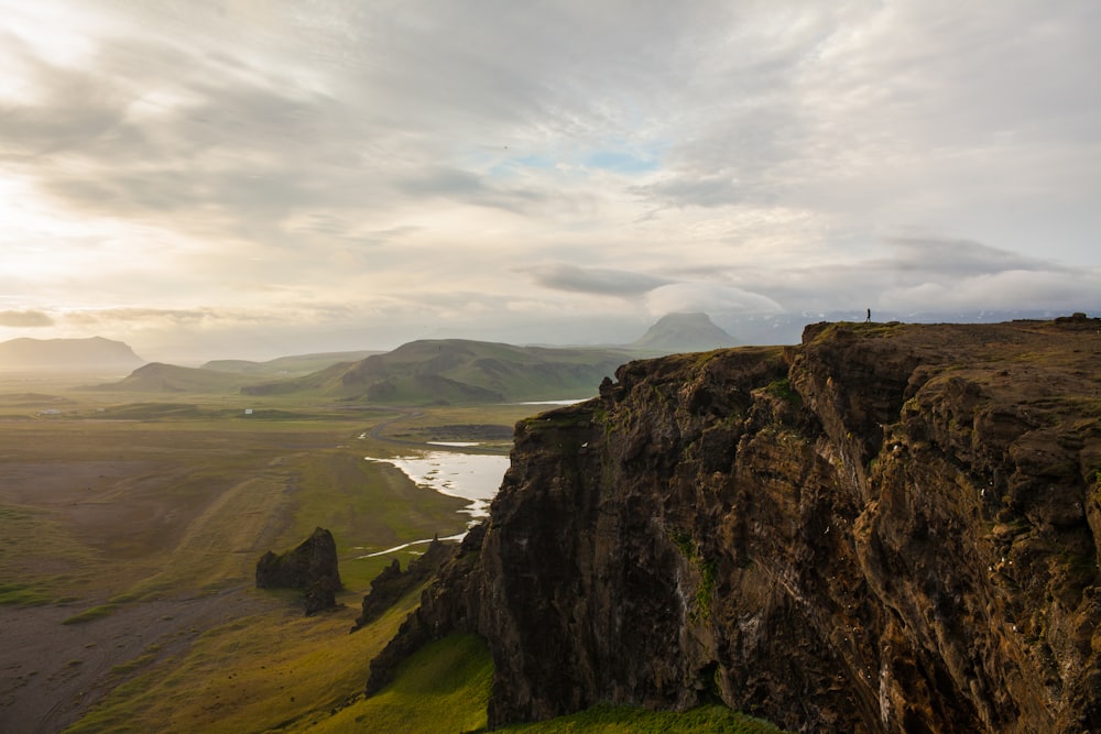 rocky cliff facing green grass fields