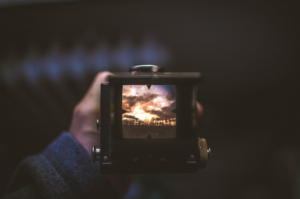 The viewfinder of a camera shows a photo of the sunset.
