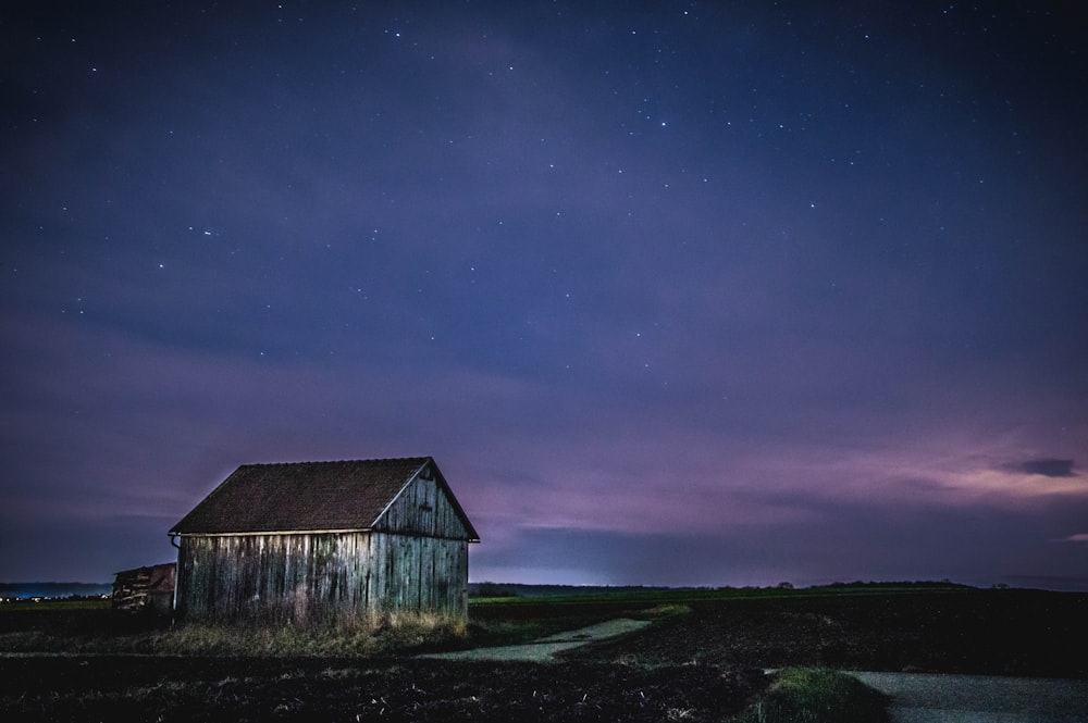 brown wooden house on green grass field under blue sky during night time