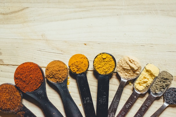 Assortment of whole and ground spices arranged neatly with measuring spoons