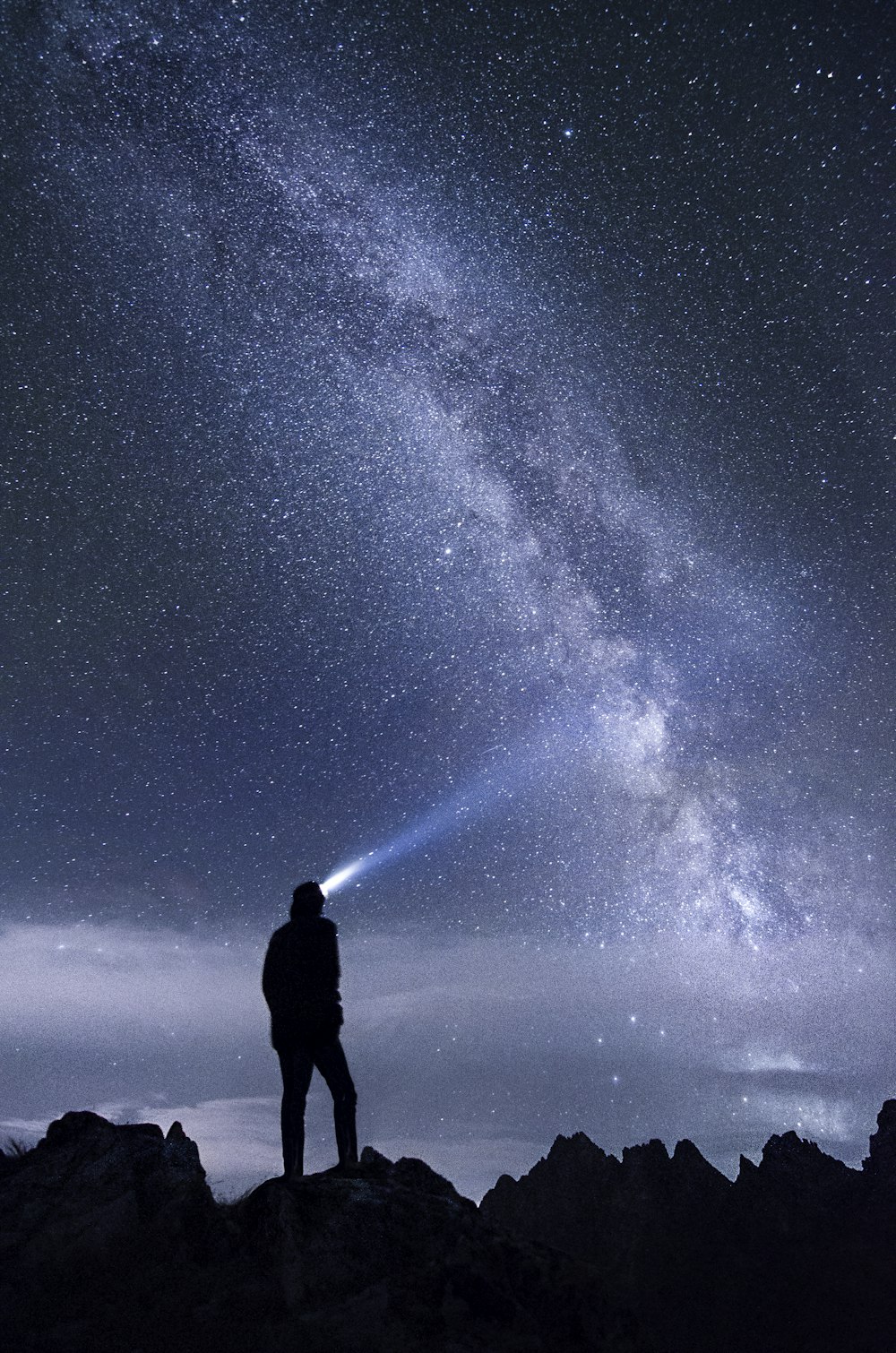 foto di silhouette dell'uomo che usa la lampada frontale in piedi sulla montagna