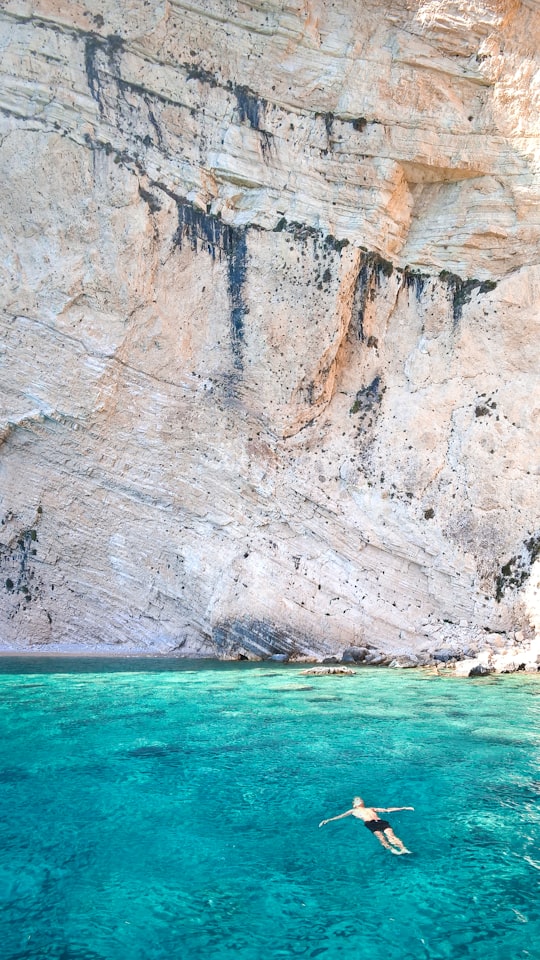 man floating over body of water near rock formation in Zakynthos Greece