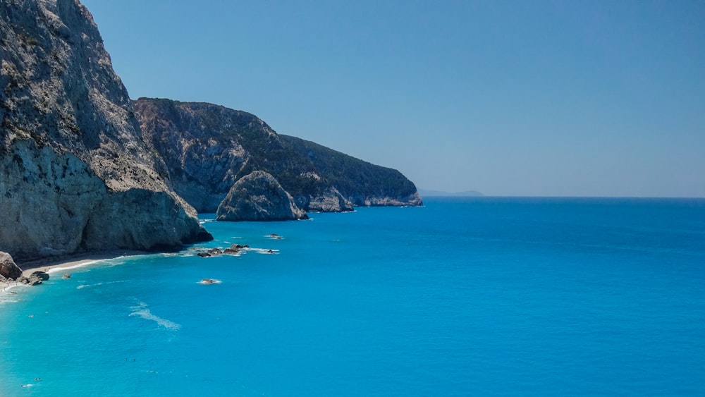 green and brown mountain beside blue sea during daytime