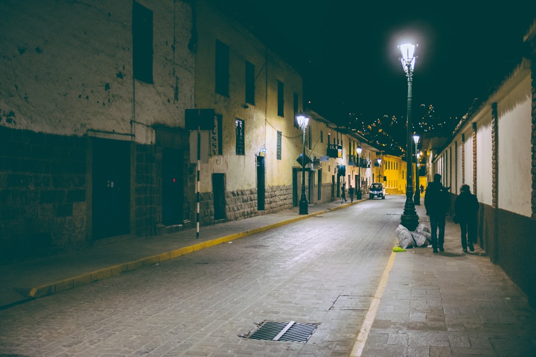 man in black jacket walking on sidewalk during night time