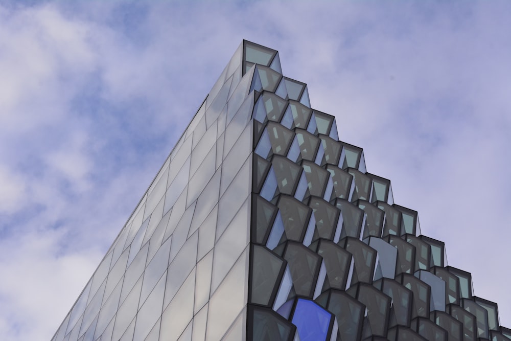 Photographie en contre-plongée d’un bâtiment en verre sous un ciel nuageux pendant la journée