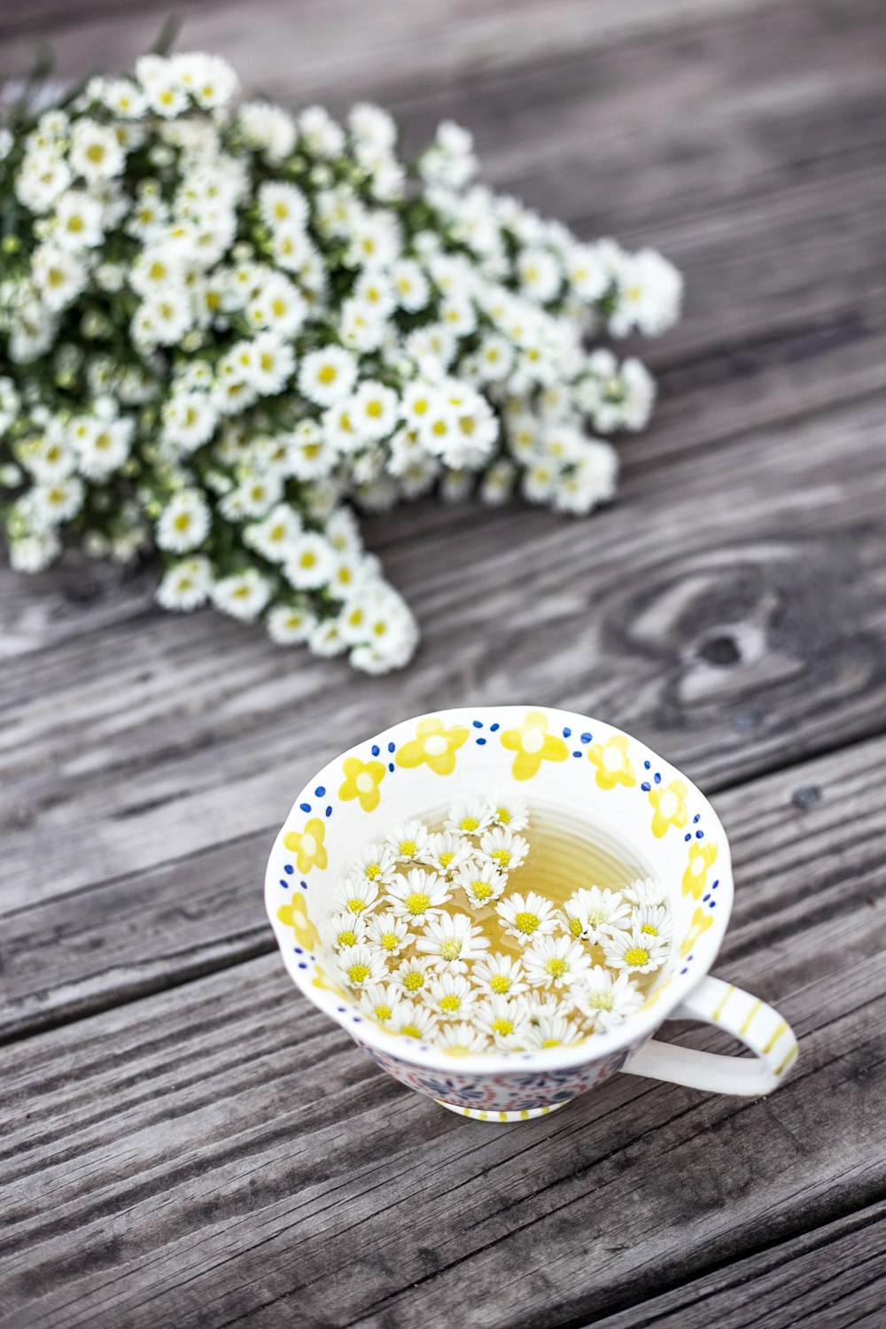 white and yellow cup with flowers on table